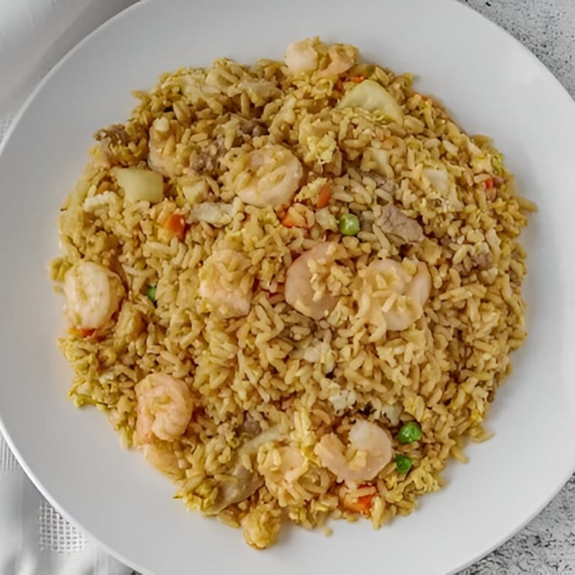 Red Wok's shrimp fried rice with vegetables and meat, served on a white plate.