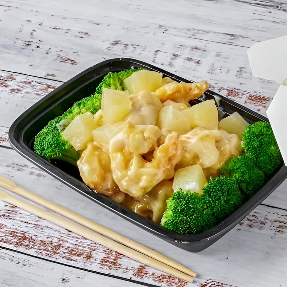 Red Wok's pineapple shrimp with broccoli in a black takeout container with chopsticks.
