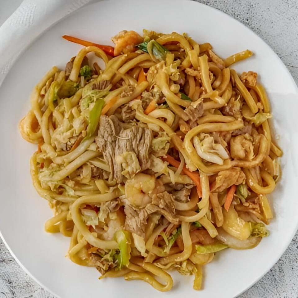 Red Wok's mixed chow mein with noodles, beef, shrimp, and vegetables on a white plate.