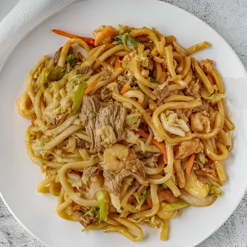 Red Wok's mixed chow mein with noodles, beef, shrimp, and vegetables on a white plate.