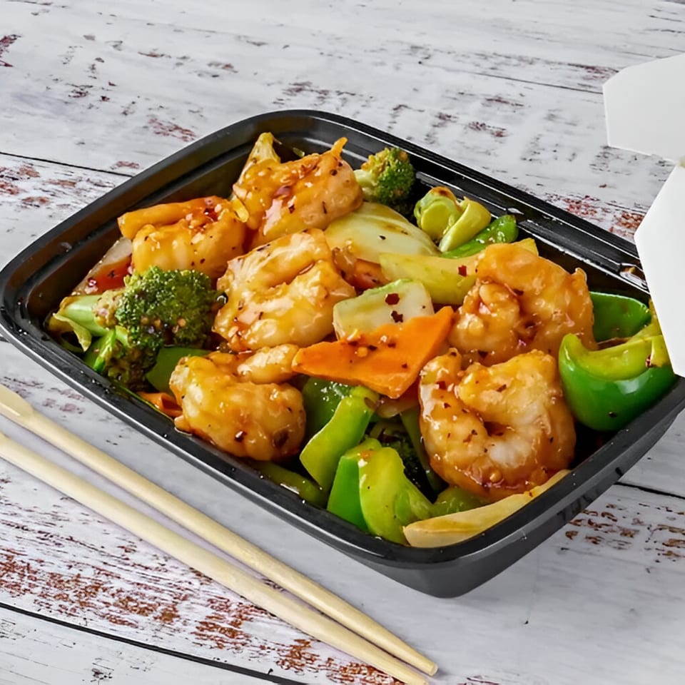 Red Wok's shrimp and mixed vegetables in a black takeout container with chopsticks.