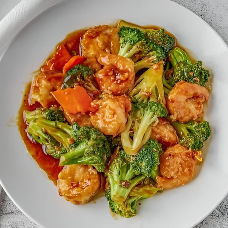 Red Wok's shrimp and broccoli stir-fry with carrots in a savory brown sauce on a white plate.